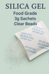 Clear silica gel beads scattered next to white 3g food-grade desiccant sachets with blue warning text.